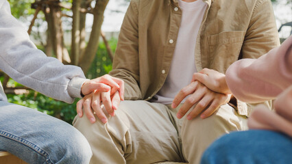 Close-up of diverse multiracial men and women group sit in circle hold hands together hope for help people in park. Support and understand at psychological therapy session, PTSD Mental health concept.