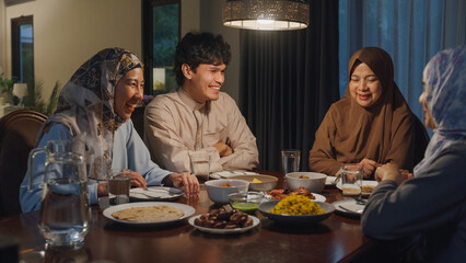 Fototapeta na wymiar Happy Asia muslim parent and their kids Ramadan dinner together in dining room at home. Family of two generation catering celebration end of Eid al-Fitr togetherness at home. Hari Raya family reunion.