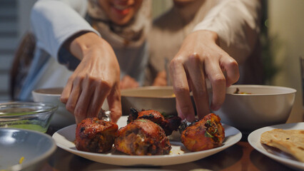 Close-up Happy Asia muslim wife talk to husband Ramadan dinner together at home. Family of two generation catering celebration end of Eid al-Fitr togetherness at home. Hari Raya family reunion.