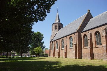 Fototapeta na wymiar Dutch late Gothic church Corneliuskerk. A Protestant church in the Zeeland village of Noordwelle. Summer. Netherlands, June. Blue sky.