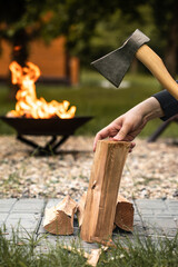 An ax with a wooden handle, chopping wood, a bonfire in the background. 
Firewood.