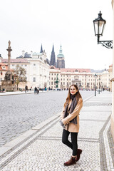 brown-haired woman in a coat on the streets of a European city