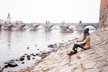 Fototapeta na wymiar woman in a coat on bank of Vltava near Charles Bridge in Prague