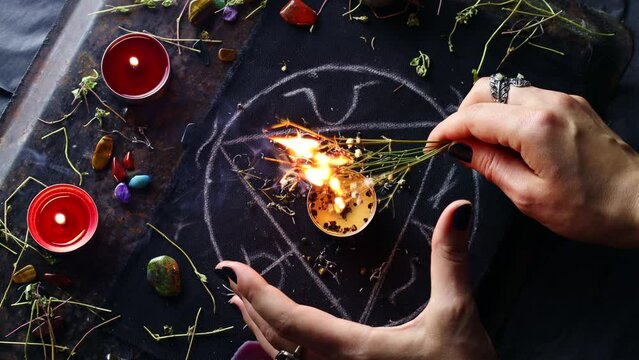 Witch hands burning herbs for a black magic ritual with the help of magical altar, candles and crystals. Sorcerer rite of witchcraft and occultism. Halloween occult, esoteric and divination concept.