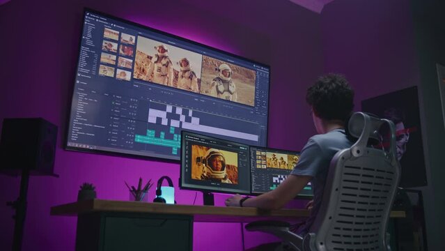 Young video maker edits movie about space mission, works at home office. Film footage and software interface with tools and sound tracks on computer and big digital screen. Concept of post production.