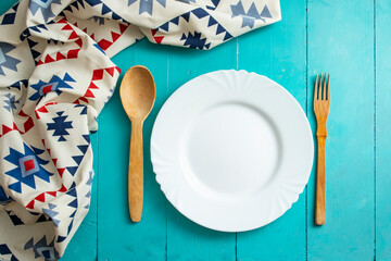Empty white plate with wooden cutlery and romanian ethnic motifs napkin