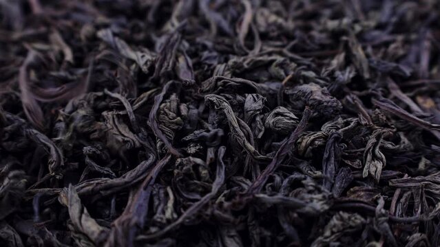 Dried black tea leaves falling down close up