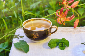 mint tea outdoors in a mug, mint leaves, lilia flowers © Orest
