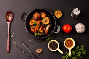 Grilled prawns served on a plate with lemon. Garlic on dark black background. Seafood. Top view.