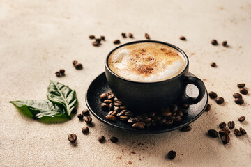 Cup of cappuccino, green coffee leaves and beans on light background. Close up