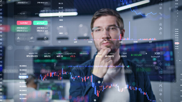 Male financial analyst works in broker agency office. 3D abstract AI graphics of real-time stocks, cryptocurrency charts on glass wall. VFX animation. Computers and big digital screens on background.