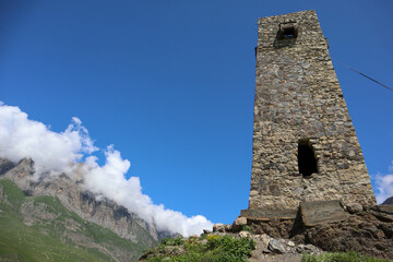 medieval stone battle tower in the city of the dead Dargavs necropolis with picturesque landscape on the background