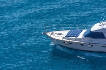 Prow of a yacht with sun loungers at the stern floating on the water surface in summer.