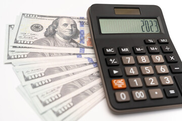 The US dollar in the year 2023. The calculator screen says 2023. A concept of money and currency trading. Calculator and US dollars. Trends, prospects and hopes. selective focus.