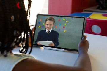 Fototapeta na wymiar Diverse schoolchildren with tablet having tablet video call over board