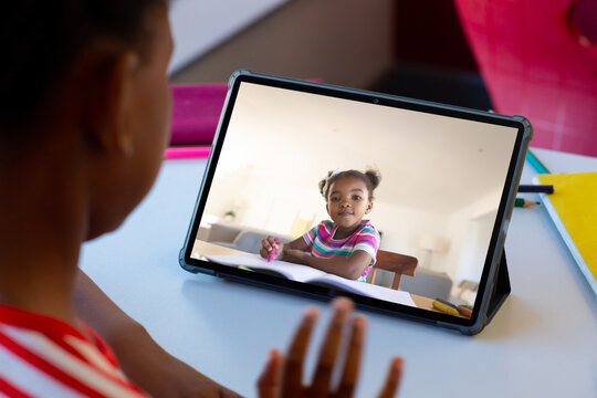 African american schoolgirls waving hand and having tablet video call
