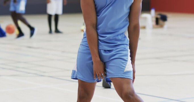 African american male basketball player bouncing ball, training at indoor court, slow motion
