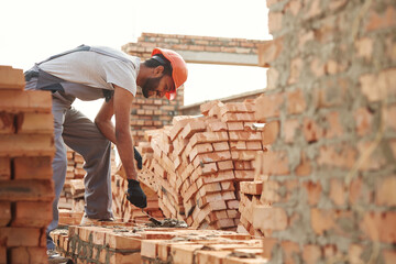 Bunch of bricks. Placing them. Handsome Indian man is on the construction site