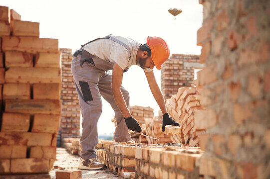 Side View, Working And Placing The Bricks. Handsome Indian Man Is On The Construction Site