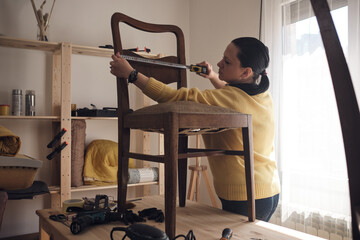 Woman working in a small home workshop for furniture repairing and restoration.