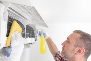 Service guy cleaning and maintaining air condition unit.