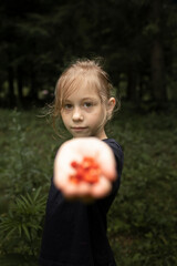 Little girl holding a hand of berries. Spending time in nature - 618052527