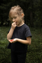 Little girl in the forest eating berries. Life in nature