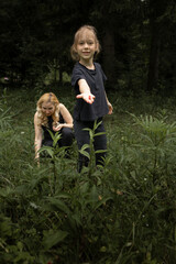 Little girl in the forest picking berries with her mother. Family time outdoors in nature - 618052556