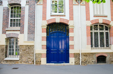 Naklejka premium Paris, France, June 08, 2023. Old blue door of brick house in Paris.