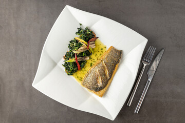 Grilled sea bass fillet served with garnishes in a fine dining restaurant