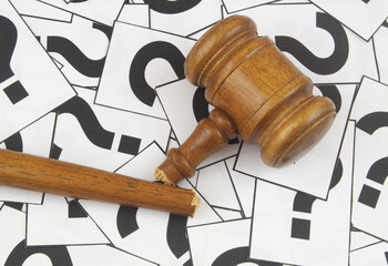 Close up of broken judge gavel on question marks background. 