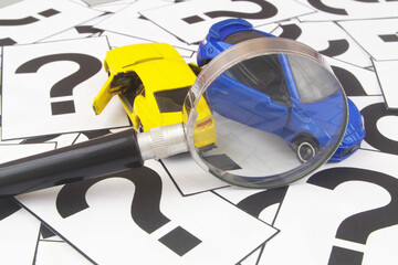 Two collided cars under magnifying glass on question marks. 