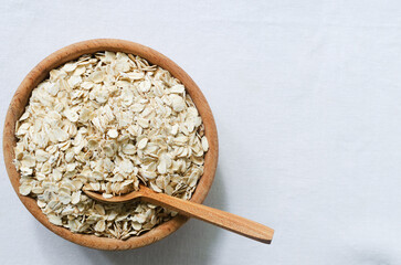 Raw oatmeal on a wooden bowl with a teaspoon on a white background. Concept of healthy eating....