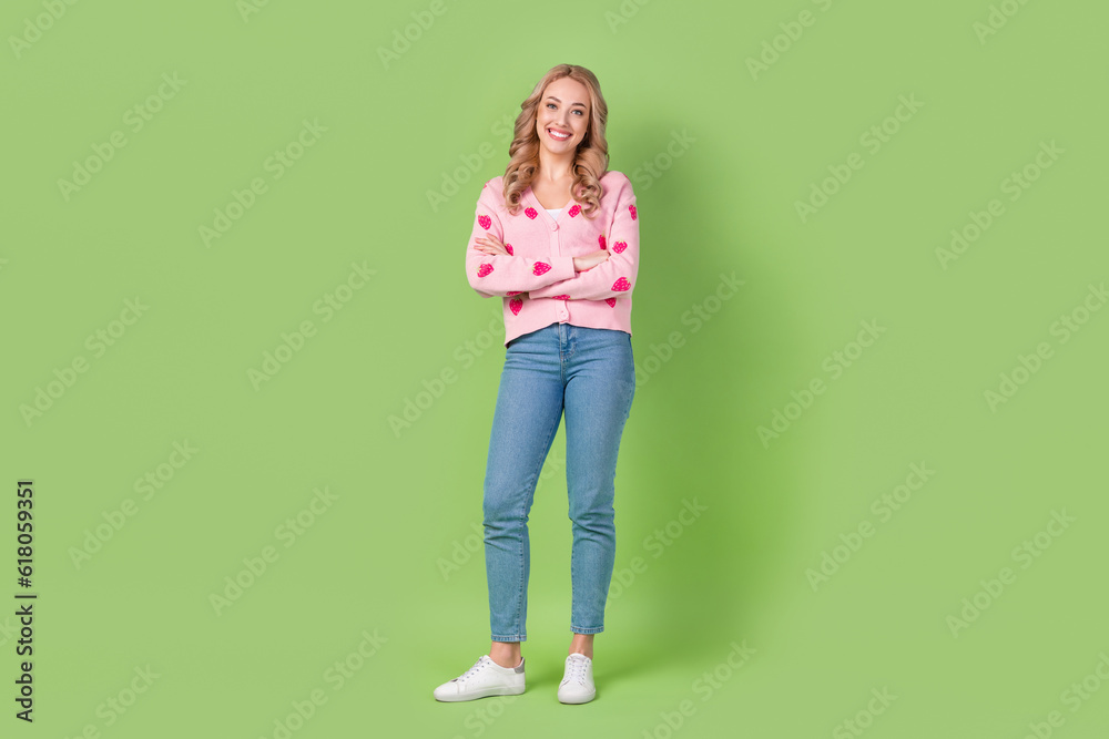 Sticker Full body cadre of satisfied young girl wearing trendy pink shirt folded arms confident denim jeans isolated on green color background