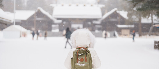 Woman tourist Visiting in Sapporo, Traveler in Sweater looking Hokkaido Shrine with Snow in winter season. landmark and popular for attractions in Hokkaido, Japan. Travel and Vacation concept - obrazy, fototapety, plakaty