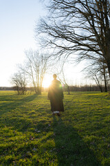 a person walking in the field in the evening, a wizard, 