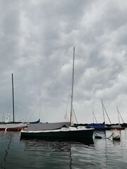 a group of boats floating on top of a lake under cloudy skies