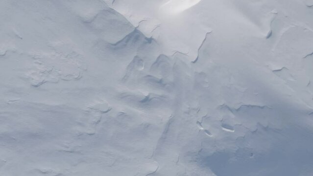 Aerial shot moving slow motion over pure white snow surface background patterns