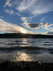 the sun setting over the ocean with rocks and pebbles in the water