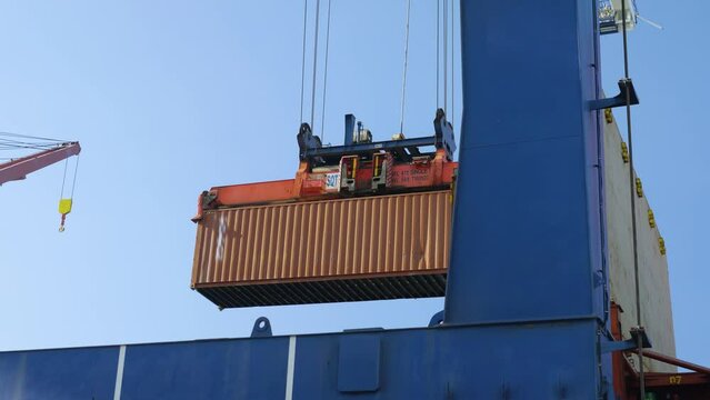 4K footage of port crane lifting cargo container. Loading and unloading of freight at dock stock video.  
