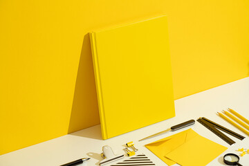 Yellow book cover mockup and stationary flat lay on yellow background