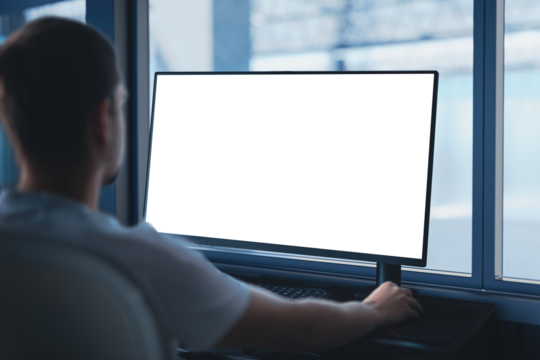 An engineer works on a computer with an empty blank screen - template, at an industrial company. In the background, there is a view of the production hall.