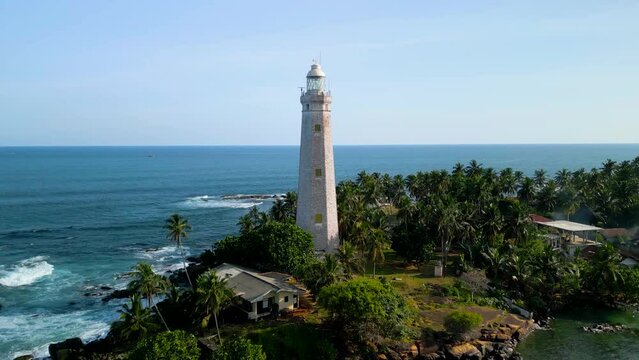 Aerial video of Dondra Lighthouse surrounded by tropical trees and the sea, Sri Lanka