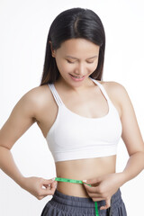 Fototapeta premium Beautiful young Asian woman measuring her waist