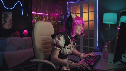 Caucasian girl wearing maid costume with pink wig and cat ears playing video game during live streaming
