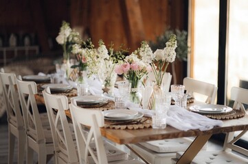 Interior of restaurant with wedding table and white chairs adorned with flowers