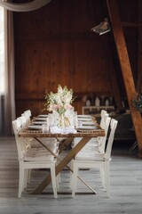 Interior of restaurant with wedding table and white chairs adorned with flowers