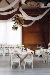 Interior of restaurant with wedding table and white chairs adorned with flowers