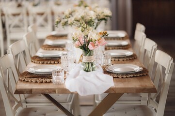 Interior of restaurant with wedding table and white chairs adorned with flowers
