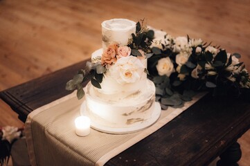 three layers cake with flowers on table in room with wood floors